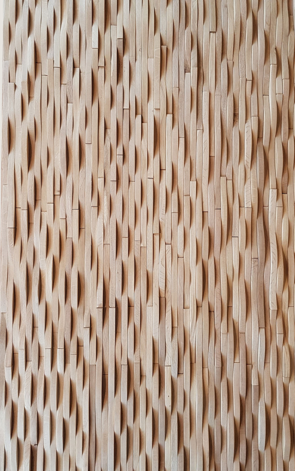 A close-up image of a 3D wavy wall cladding made from oak wood strips, finished with a matte hard wax oil.